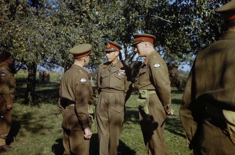 Abb. 2: König Georg VI. von Großbritannien (m.) in Begleitung des Befehlshabers des 12. Korps der 2. Armee, Generalleutnant N. Ritchie (r.), im Gespräch mit dem Verantwortlichen für zivile Angelegenheiten des 12. Korps, Oberst W. H. Bordass (l.), am 13. Oktober 1944 während eines Besuchs beim 12. Korps in der Nähe von Nijmegen (Imperial War Museum, gemeinfrei, https://commons.wikimedia.org/wiki/File: HM_King_George_VI_With_the_British_Liberation_Army_in_Holland, _13_October_1944_TR2399.jpg) Abb. 2: König Georg VI. von Großbritannien (m.) in Begleitung des Befehlshabers des 12. Korps der 2. Armee, Generalleutnant N. Ritchie (r.), im Gespräch mit dem Verantwortlichen für zivile Angelegenheiten des 12. Korps, Oberst W. H. Bordass (l.), am 13. Oktober 1944 während eines Besuchs beim 12. Korps in der Nähe von Nijmegen